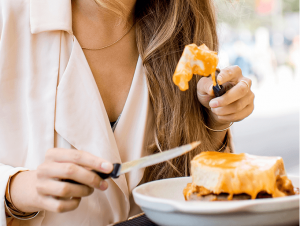 Woman eating Francesinha, one of the most traditional Portuguese dishes, by the Douro river in Porto.