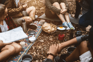 Group of friends eating and drinking in camping.