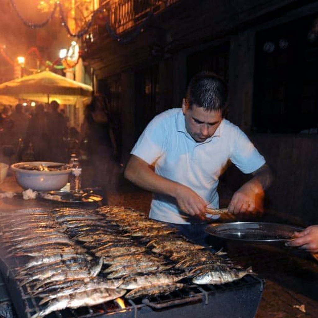 Homem a assar sardinhas e a colocá-las numa travessa, nas festas de São João do Porto